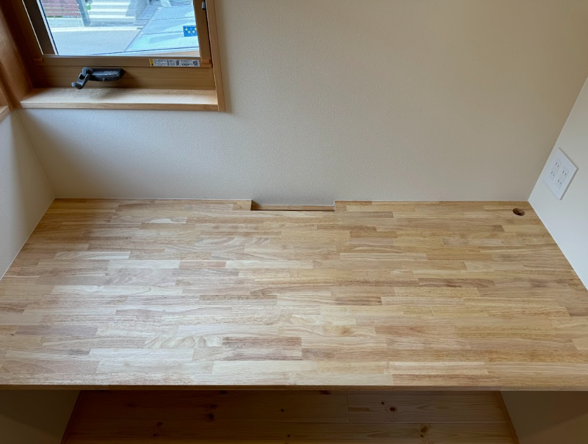 コンセントを通す穴が中央の壁側にあります。コンセント口はデスクの上と下に4つずつ設置。